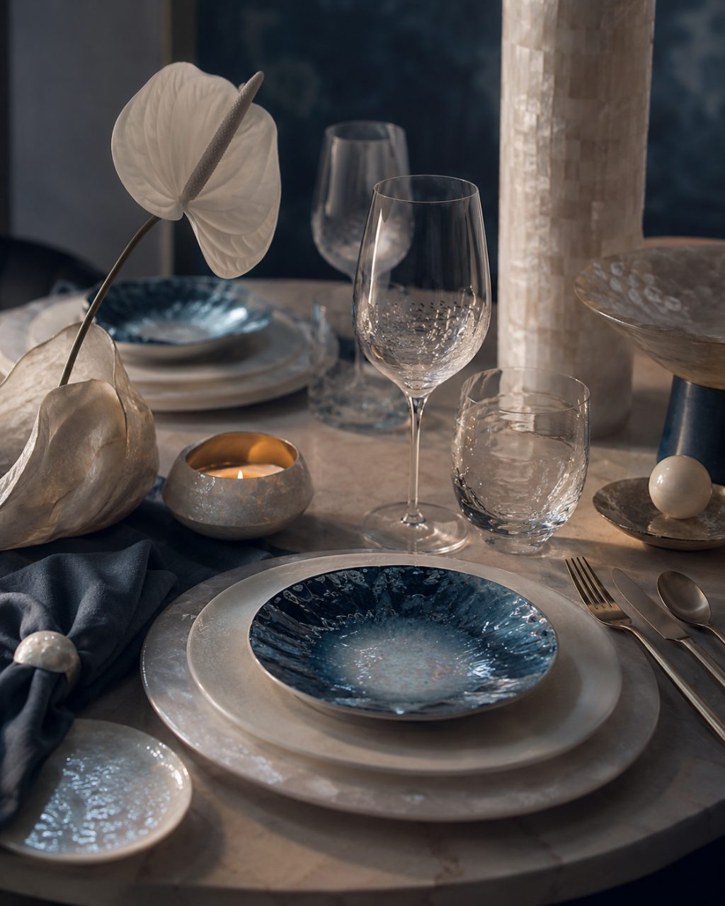 Abu Dhabi Blue — a place setting in deep sea tones with a brass napkin ring and white wine in low evening light.